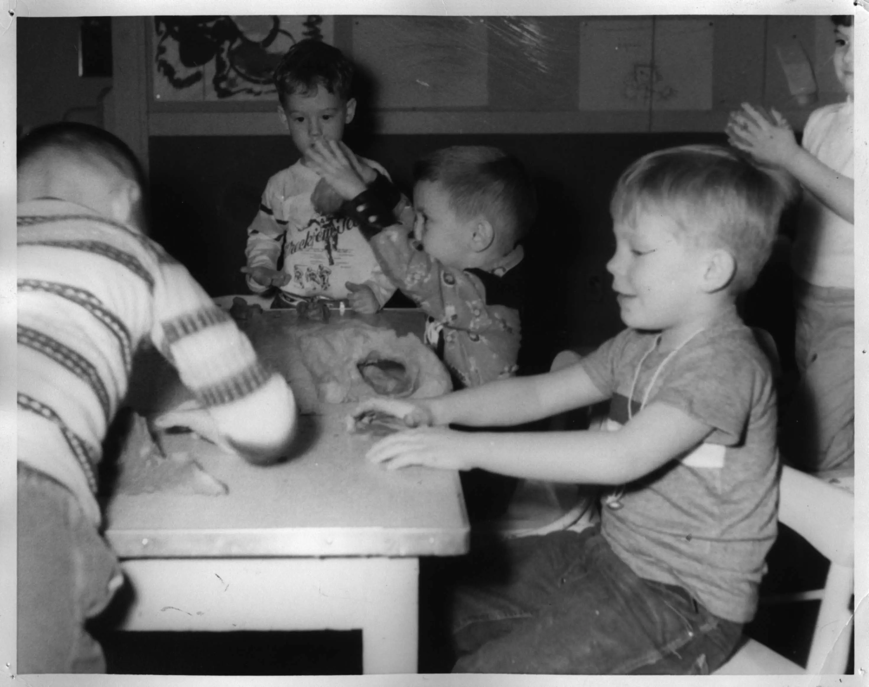 Four young children sitting together around a low table, playing and shaping dough during a class at Little Lovett.